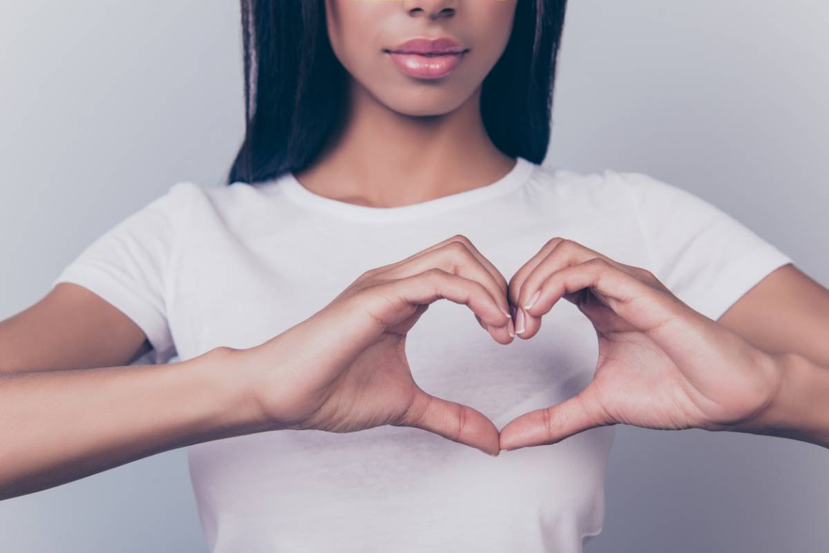 Woman make a heart symbol to represent loving your breasts.