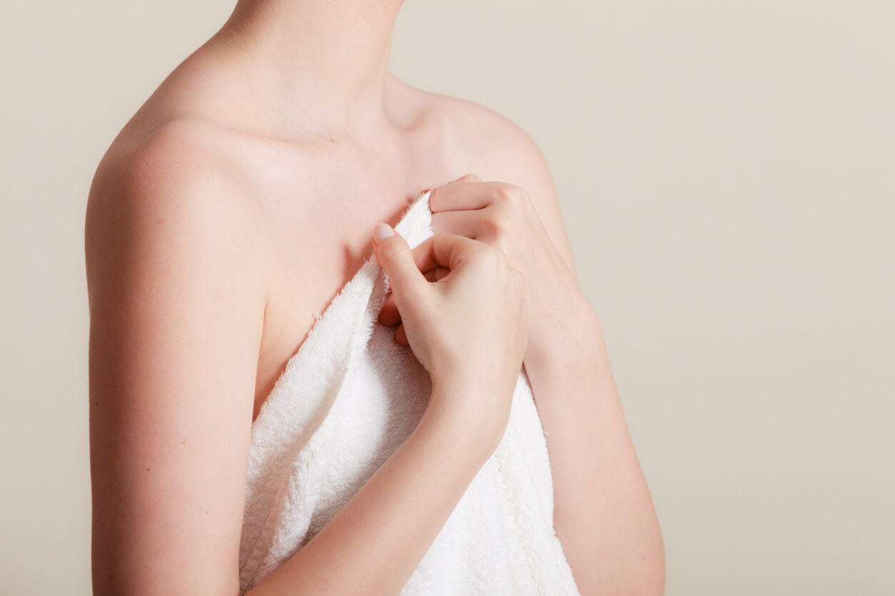woman covering her breasts with a towel. how fat transfer breast augmentation corrects underdeveloped breasts